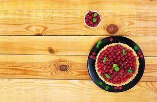 Delicious tart with custard and raspberry on wooden background photo