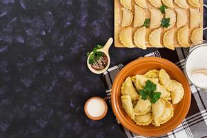 Delicious dumplings with cabbage on dark background. Top view photo