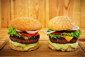 Delicious handmade burger on wooden background. Close view photo