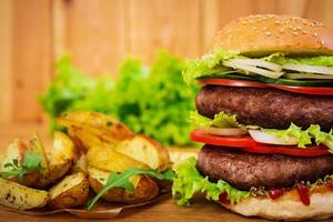 Delicious handmade burger on wooden background. Close view