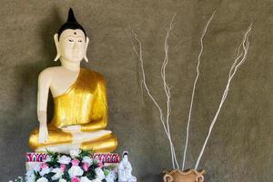 Statue of Buddha with rough cement wall. photo