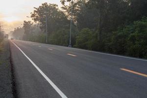 carretera asfaltada con sol naciente en el campo. foto