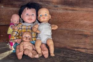 un grupo de muñecas sentadas en una vieja casa de madera. foto
