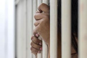 The hand of the accused woman caught the bars of the prison room. photo