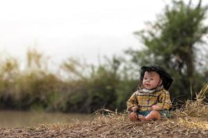 A doll like a young girl sitting on a hay. photo
