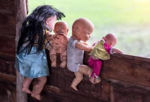 Behind old baby dolls climbing on wooden wall. photo