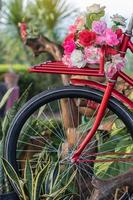 hermosas flores artificiales en una bicicleta antigua roja. foto