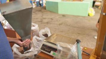 vendedor en el mercado vierte café molido en un paquete de aluminio en el cáucaso video
