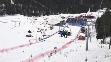 bansko, bulgarien, 2019 - professionella skidåkare nerför backen i en berömd skidtävling. åskådare ur stollift synvinkel. video