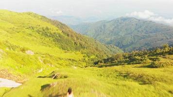 aufsteigende Fliege über junge Frau von der Rückseite mit landschaftlich grünem Berghintergrund video