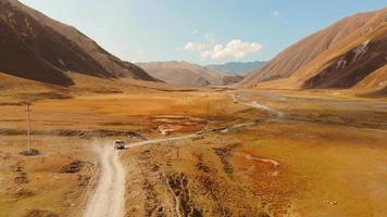 White vehicle slowly drive on gravel terrain with stunning nature landscape. Adventure off-road travel video