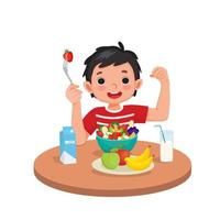 lindo niño comiendo frutas y verduras saludables mostrando tenedor con fresa y su fuerte puño de brazo muscular vector