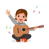 niña feliz tocando la guitarra sentada en el suelo agitando la mano con una expresión facial sonriente vector