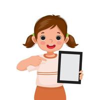 linda niñita sosteniendo una tableta digital con el dedo apuntando a una pantalla vacía o copiando espacio para textos, mensajes y contenido publicitario. concepto de niños y dispositivos electrónicos para niños vector