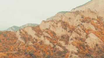 vista aérea de coloridos acantilados de otoño en un día nublado con fondo de cielo gris. cambio de colores de la flora de las estaciones en las montañas del cáucaso