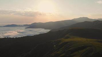 Luftflug über den malerischen Berg Gomi mit stehendem Auto und Sonnenaufgang über den Wolken im Hintergrund video