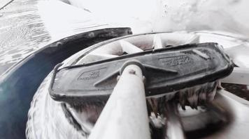 brosse savonneuse dans le lavage de voiture laver les disques de roue gris sales à l'extérieur.