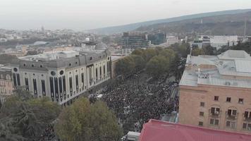 1 de noviembre de 2020. tbilisi.georgia.vista aérea frontal ascendente hasta multitudes de personas reunidas para protestar frente al edificio del parlamento.protestas electorales posteriores al parlamento en el cáucaso. video