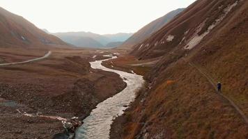 een vrouwelijke backpacker loopt het pad af in een prachtige vallei met een rustige landschapsachtergrond. gezonde levensstijl en bergen activiteiten concept video