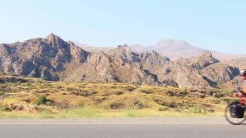 väg från sidan med förbipasserande bilar och manlig cyklist i Armeniens natursköna natur utomhus video