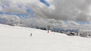Tracking aerial view beginner female skiers skiing down hill on blue slope in Gudauri ski resort. Travel holiday destination.