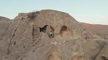 Aerial view of female tourist standing and looking through cave surrounded by rock formations video