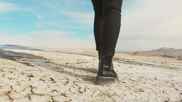 Back side of shoes stepping on white volcanic terrain in slow motion. Background cinematic travel concept video