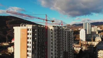 vista ravvicinata di due gru statiche con un nuovo edificio in costruzione. caucaso di sviluppo immobiliare. video