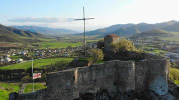 Aerial static view Kveshi fortress with with georgian flag and cross on top in spring. Historical and cultural heritage n Georgia video