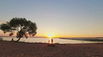 zoom in view zonsondergang timelapse door schilderachtig meer in litouwen met passerende mensen. video