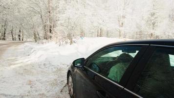 jovem caucasiana dentro do carro olhando pela janela para o céu. previsão do tempo e condições de condução no inverno