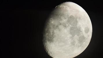 vista estática de cerca la luna satelital de la tierra llena en el marco. fase de media luna menguante. cosmos desde la vista del telescopio video