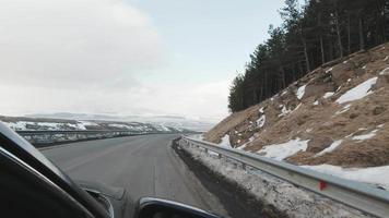 Winter landscape view from passengers seat in car to snowy mountains in Georgia. Travel road trip caucasus mountains concept video
