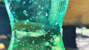 Close up bubbles of sparkling fizzy drink in green bottle. Concept of plastic containers and environment video