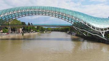 vol aérien sous le magnifique pont de la paix avec panorama sur la rivière mtkvari. monuments de l'architecture futuriste de tbilissi