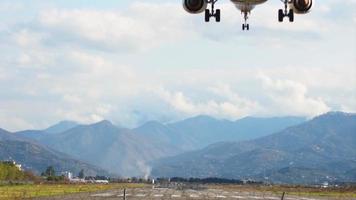 vista posteriore aereo commerciale che atterra in tempo reale sulla pista dell'aeroporto di batumi con lo sfondo del panorama delle montagne video