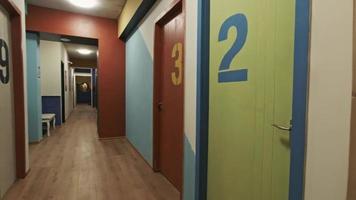 Panning view of hostel long hallway with storage and many dormitory rooms with numbers video