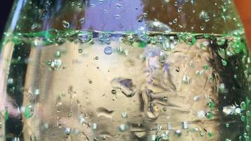 Close up bubbles of sparkling fizzy drink in green bottle with expiration date on side video