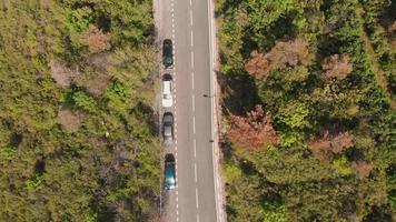 Aerial view down to cars parked on side of two line road surrounded by nature video