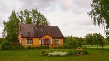 Traditional old wooden yellow house in Lithuania countryside. Lifestyle culture in rural Lithuania.