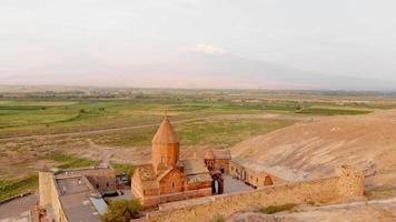 Drone revealing view historical landmark in Armenia - Khor Virap monastery with Ararat mountain peak background at sunrise