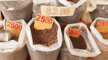 Slow motion panning view raw brown coffee beans in bags close up in food market in Armenia