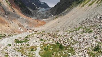 Aerial ascending view of melting Chalaadi glacier in background with river floating on foreground. Caucasus, Eurasia climate change concept video