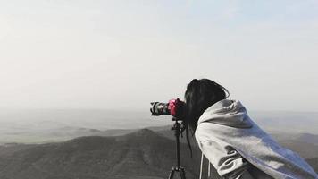 vista lateral morena mujer caucásica fotógrafo de viajes disparando fotos de paisajes al aire libre video