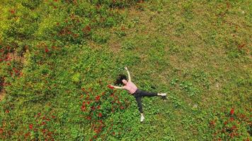 Zoom out aerial top view young caucasian woman lay in green field joyful. Well being and Feeling free and happy, optimistic nature shot.