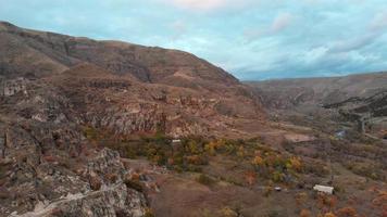 sobrevoo aéreo sobre o vale em vardzia cercado por montanhas cênicas e céu dramático. viagens e flora no sul do cáucaso