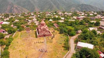turistas de visão estática aérea pelo marco da igreja odzun com panorama de casas de vila. famosa basílica armênia construída v - século vii na província de lori video