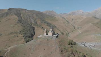 vista aérea do mosteiro da trindade gergeti até a colina com panorama cênico das montanhas. video