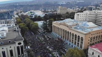 1 de noviembre de 2020. tbilisi.georgia.vista aérea frontal ascendente hasta multitudes de personas reunidas para protestar frente al edificio del parlamento.protestas electorales posteriores al parlamento en el cáucaso. video