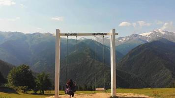 movimento rápido voar através de mulher morena balançando em balanços mestia icônicos em montanhas cênicas. destino de viagem da Geórgia. video